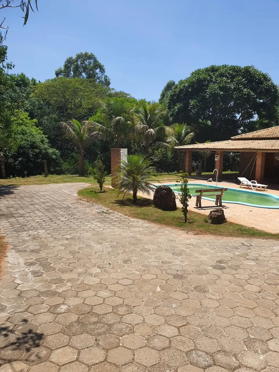 Pátio pavimentado junto à piscina e à casa do sítio à venda em Torrinha/SP